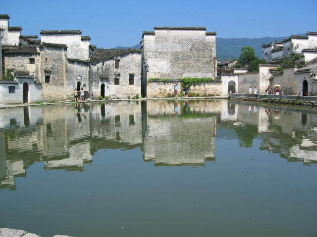 Village de Hongcun, dans le sud Anhui. Photo An copyright. La Colline de Leigang à l'extrême ouest du village de Hongcun représente la tête d'un boeuf, et les deux arbres qui s'y dressent les cornes. Quatre ponts sur le ruisseau Jiyin font penser à ses quatre pattes, et les maisons du village en forment le corps. Les méandres du ruisseau à travers le village peuvent être vus comme ses intestins, et les lacs comme les diverses poches de son estomac.